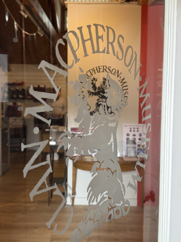 Etched glass panel featuring the Clan Macpherson wildcat logo at the Museum’s Laggan Road entrance.